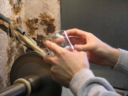 To hand cut crystal, the artisan looks through the glass, at the cutting wheel 